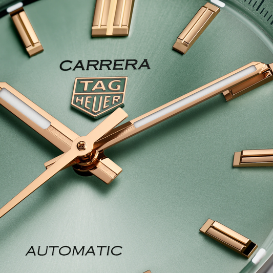 close-up of the green dial showcasing the sunray finish, applied gold-tone indices, slender hands and date window at 6 o’clock