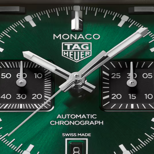 Close-up of the TAG Heuer Monaco green sunray dial featuring black chronograph sub-dials, luminous hands, and date display.