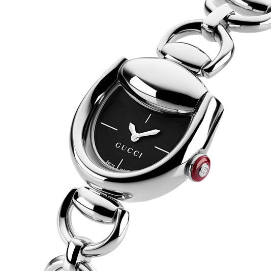 Close-up angled view of the Gucci stainless steel bracelet watch featuring a black minimalist dial, sculptural rounded case, polished silver finish, and red enamel crown.