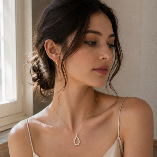 18ct yellow gold teardrop pendant  0.40ct of brilliant-cut diamonds on a modal in a cream dress with a low bun 