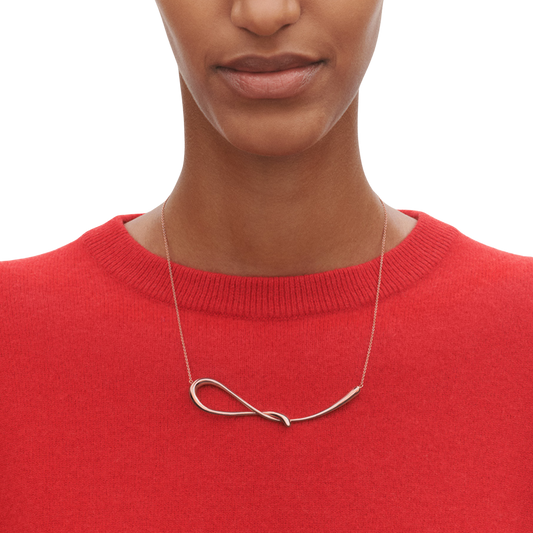 Unlike a traditional pendant, the Mercy design follows a soft, organic curve that sits beautifully against the neckline. The polished silver finish reflects the light naturally, giving the piece a subtle shine without feeling overly formal.