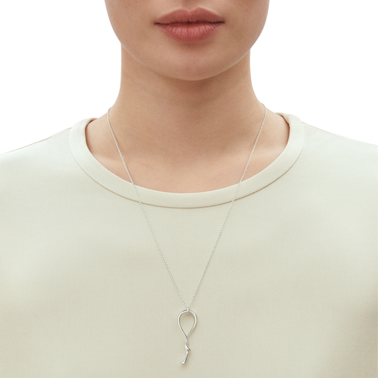 With its elegant swirl silhouette and polished finish, this necklace catches the light beautifully as it moves. The elongated shape creates a flattering look at the neckline, adding interest without being overly bold. It's the sort of piece that works just as well with a simple white shirt as it does with an evening outfit.