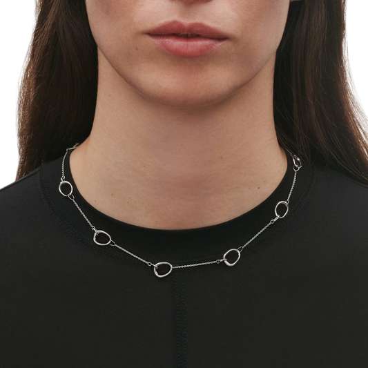 Front lifestyle view of a model wearing the Georg Jensen Offspring Sterling Silver Station Necklace, showcasing organic open-circle sterling silver stations along a delicate chain.