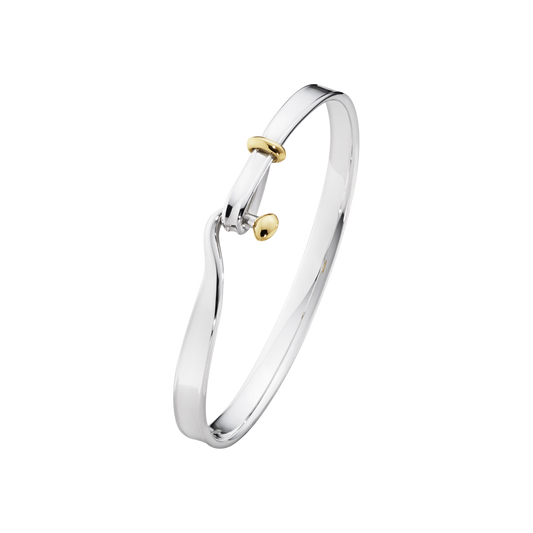 The Georg Jensen Torun Bangle combines sterling silver and 18ct yellow gold in an elegant open design, creating a timeless piece inspired by connection and unity. Available in medium.