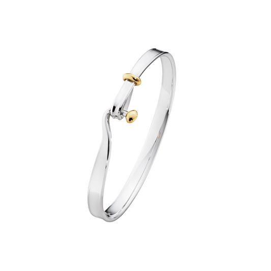 The Georg Jensen Torun Bangle blends sterling silver and 18ct yellow gold in a design that's instantly recognisable for its graceful simplicity. The flowing open silhouette curves naturally around the wrist, while the touch of warm gold adds a beautiful contrast to the cool polished silver.