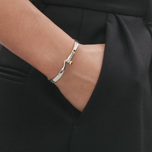 What makes this piece so versatile is its combination of precious metals. The sterling silver and 18ct yellow gold work together effortlessly, allowing the bangle to complement both silver and gold jewellery. It's an easy piece to wear on its own or layered with your favourite bracelets for a more personal look.