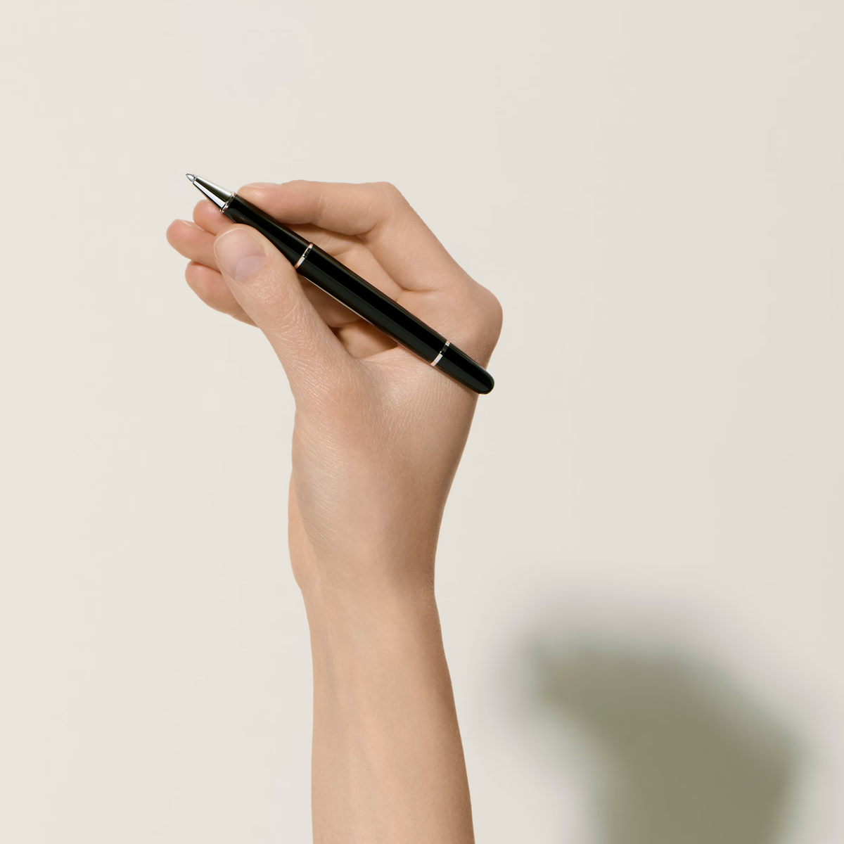 Hand holding the Montblanc Meisterstück Platinum-Coated Classique rollerball pen with glossy black resin finish and platinum trim.