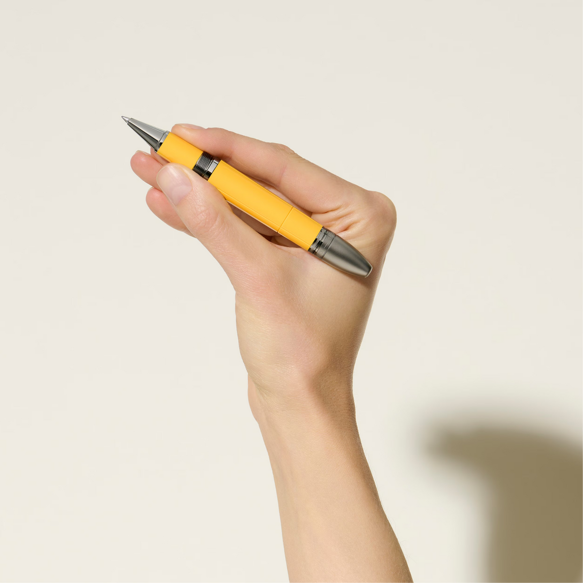 Hand holding the Montblanc Great Characters Enzo Ferrari Giallo Modena rollerball pen with yellow resin barrel.