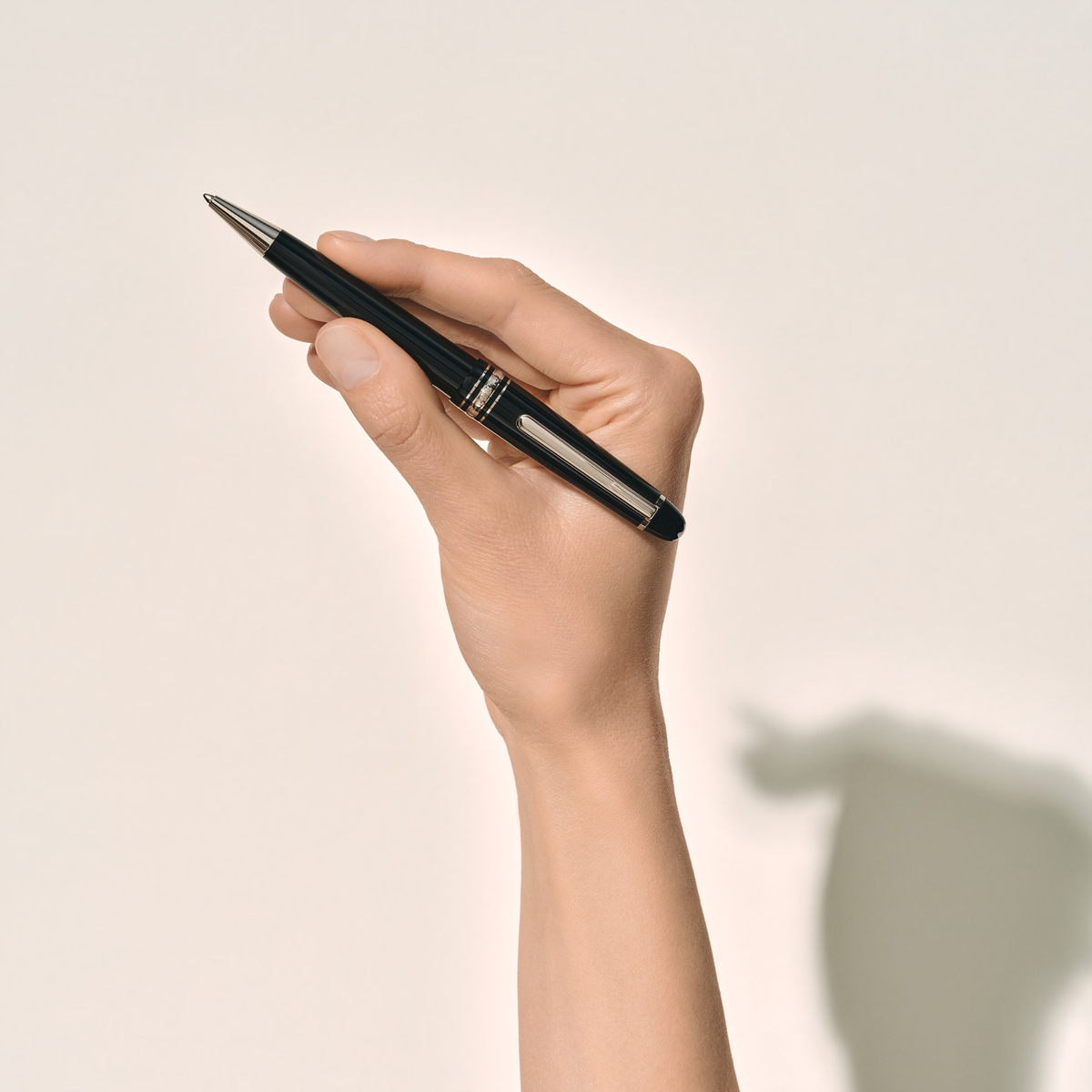 Hand holding the Montblanc Meisterstück Platinum-Coated Midsize ballpoint pen in black precious resin.