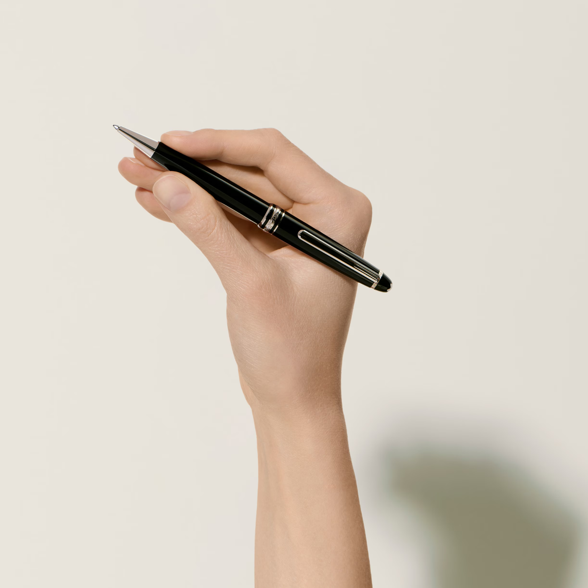 Hand holding the Montblanc Meisterstück Platinum-Coated Classique ballpoint pen in black precious resin.