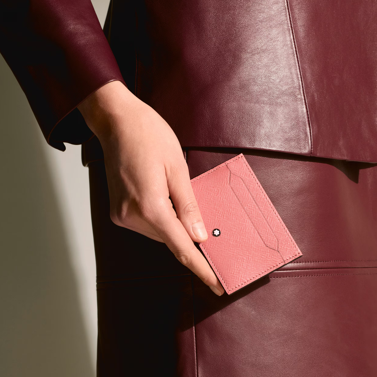 The Montblanc Sartorial 5CC Card Holder Blush Leather in a hand with a purple suit