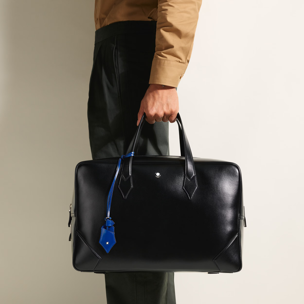 Person carrying the Montblanc Meisterstück 149 black leather bag by its top handles.