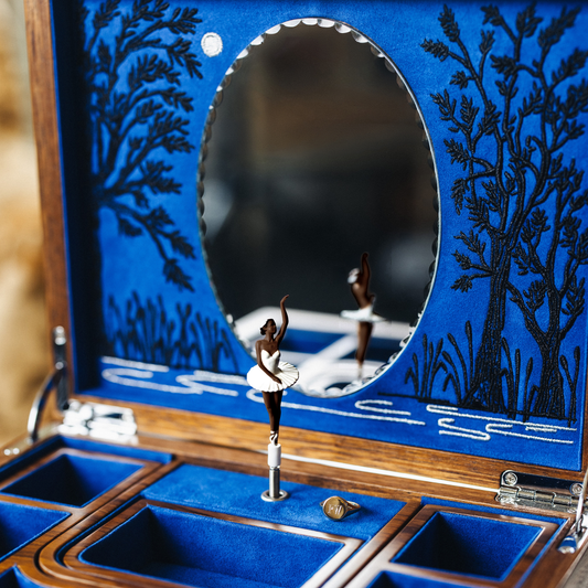 Open the lid to reveal an enchanting theatre-inspired interior, complete with an embroidered Swan Lake backdrop and scalloped-edge mirror.
The musical mechanism plays Tchaikovsky's Swan Lake while a hand-painted ballerina gracefully rotates on display.
The box includes two interchangeable ballerina figurines in different skin tones, offering a more personal and inclusive experience.