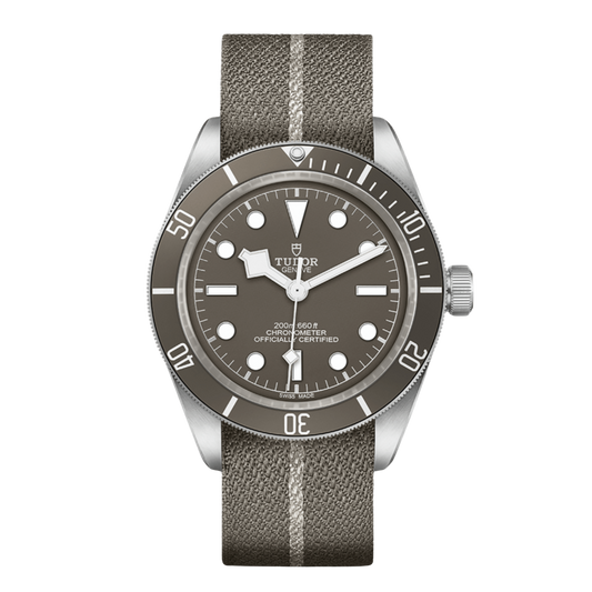 Tudor stainless steel dive watch with taupe dial, luminous hour markers and matching unidirectional bezel on fabric strap