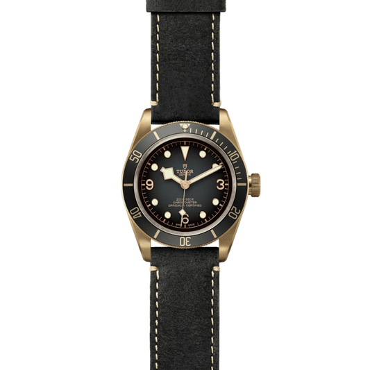 full view of Tudor watch showing the complete aged leather strap and warm bronze case profile