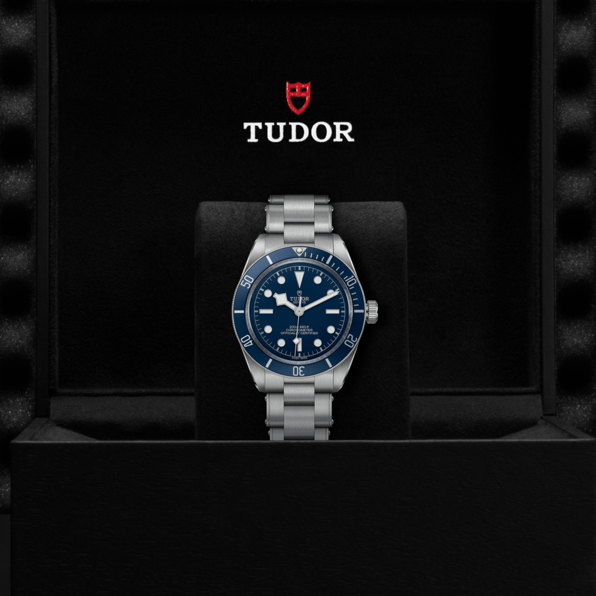 Tudor watch positioned on its side highlighting the case thickness, blue bezel edge and screw-down crown detail