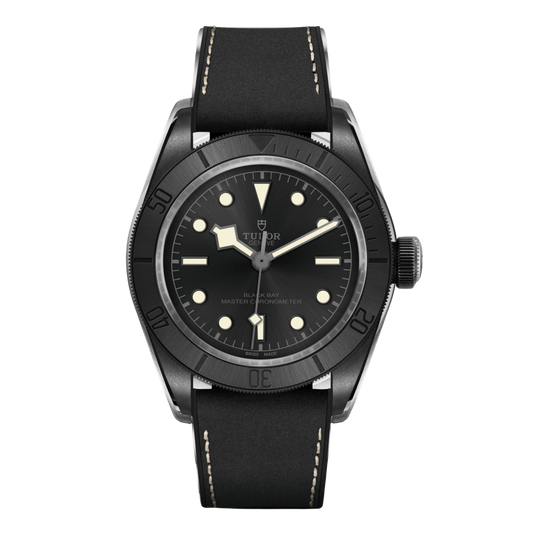 Tudor black case dive watch with black dial, luminous hour markers and black unidirectional bezel on leather strap.