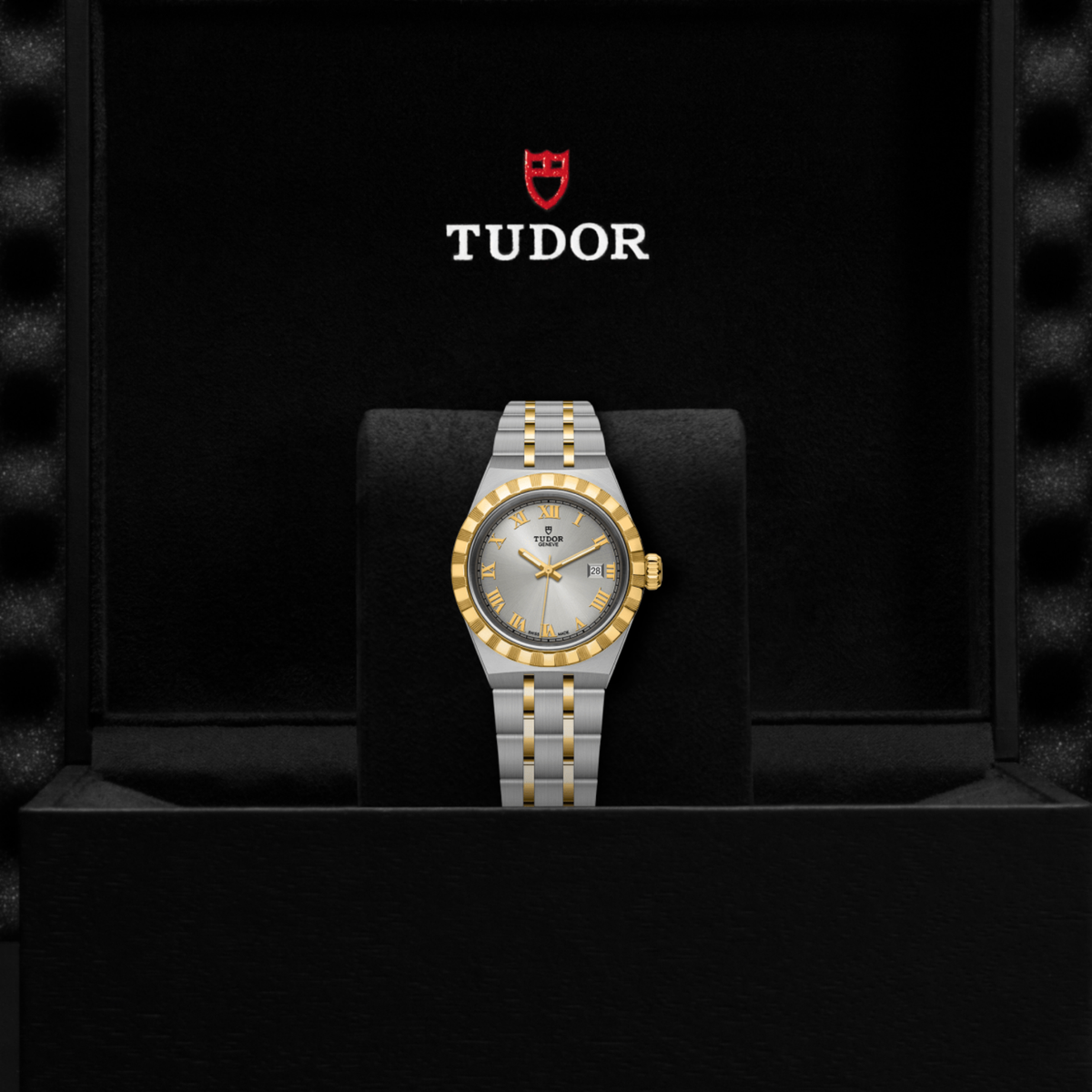 Tudor two-tone watch positioned on its side highlighting the case thickness, fluted bezel and gold crown