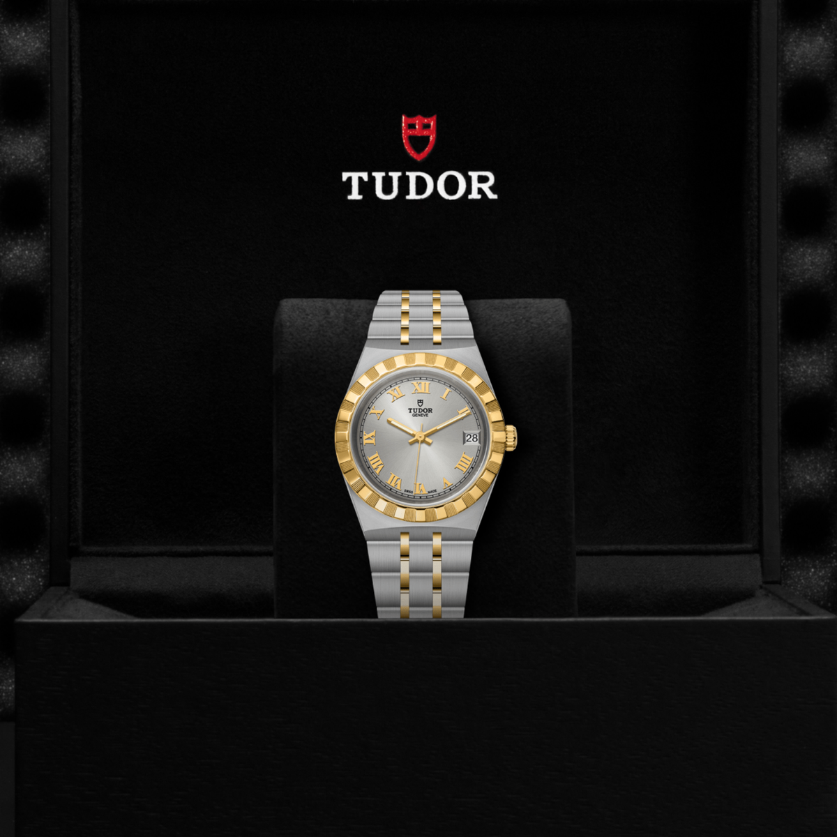 Tudor two-tone watch positioned on its side highlighting the case thickness, fluted bezel and gold crown