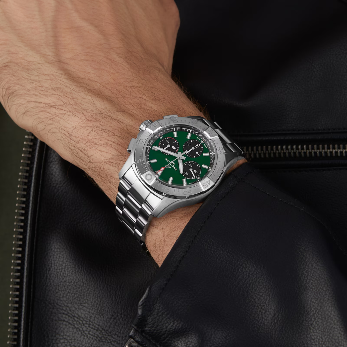 Green dial chronograph watch with stainless steel strap on wrist