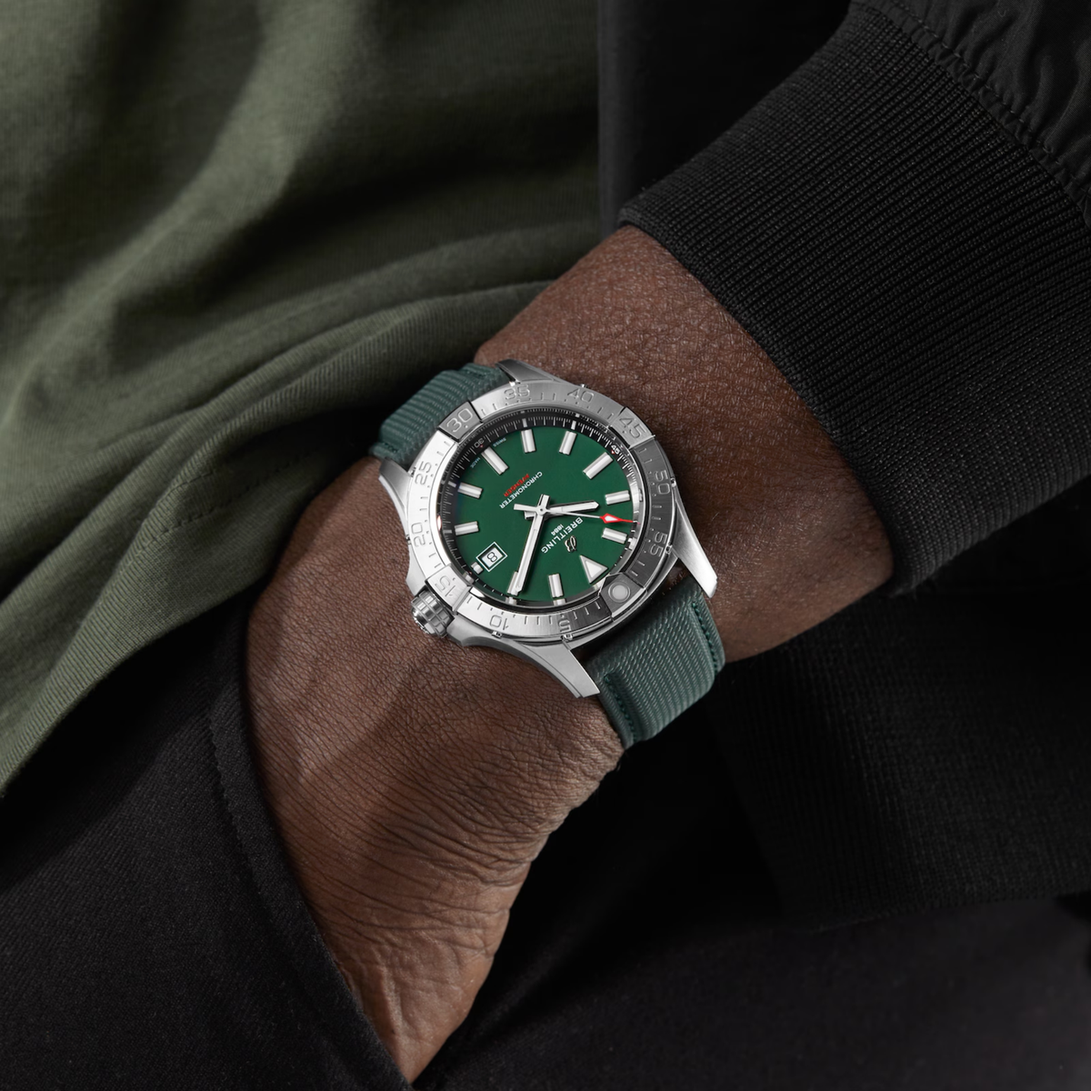 Green dial watch with silver case and fabric strap on wrist