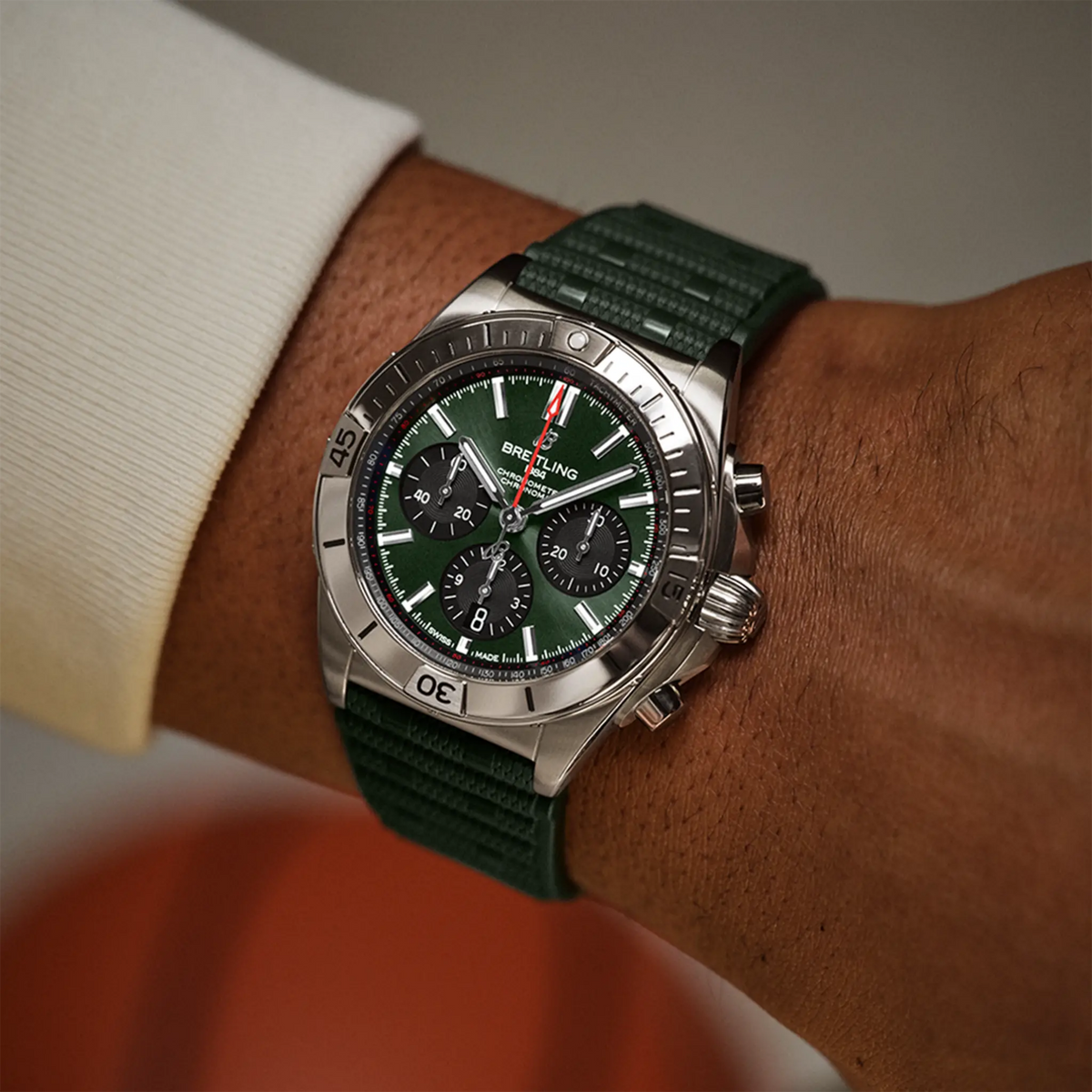Breitling Chronomat chronograph green dial watch worn on wrist with green rubber strap
