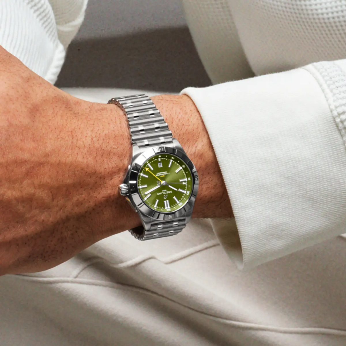 Breitling Chronomat GMT green dial watch worn on wrist with stainless steel bracelet