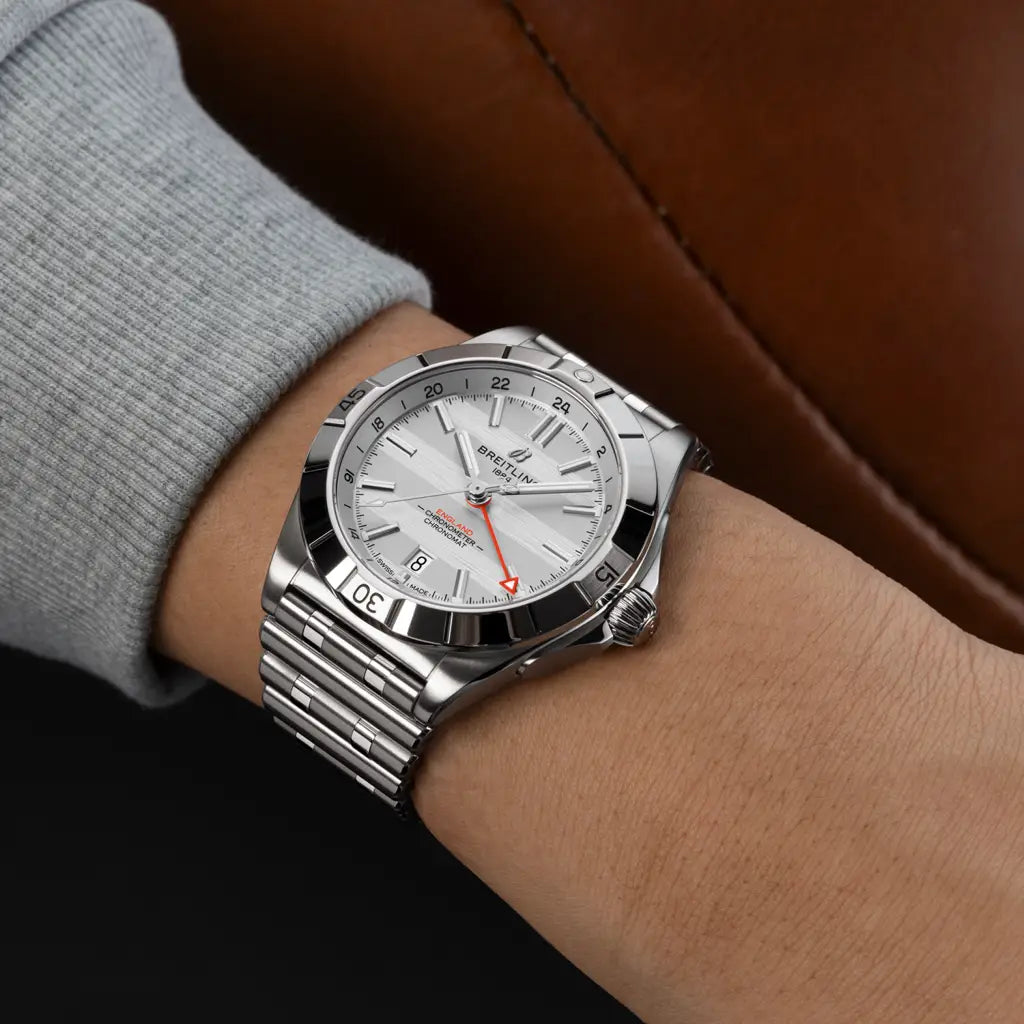 Stainless steel Breitling watch with white dial and red second hand on wrist