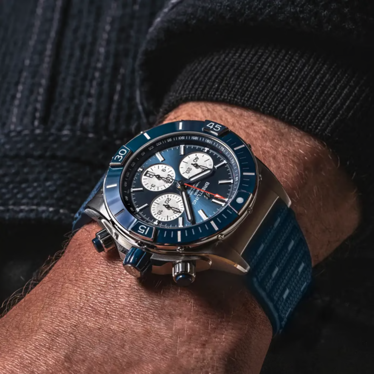 Model wearing the Breitling Super Chronomat B01 44 with a blue dial, stainless steel case, and blue rubber strap on the wrist.