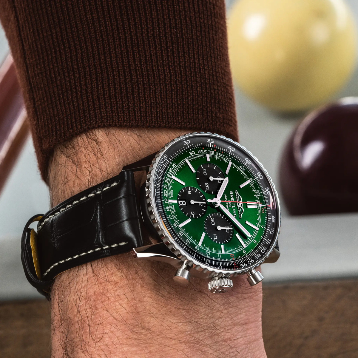Breitling Navitimer chronograph green dial watch worn on wrist with black leather strap