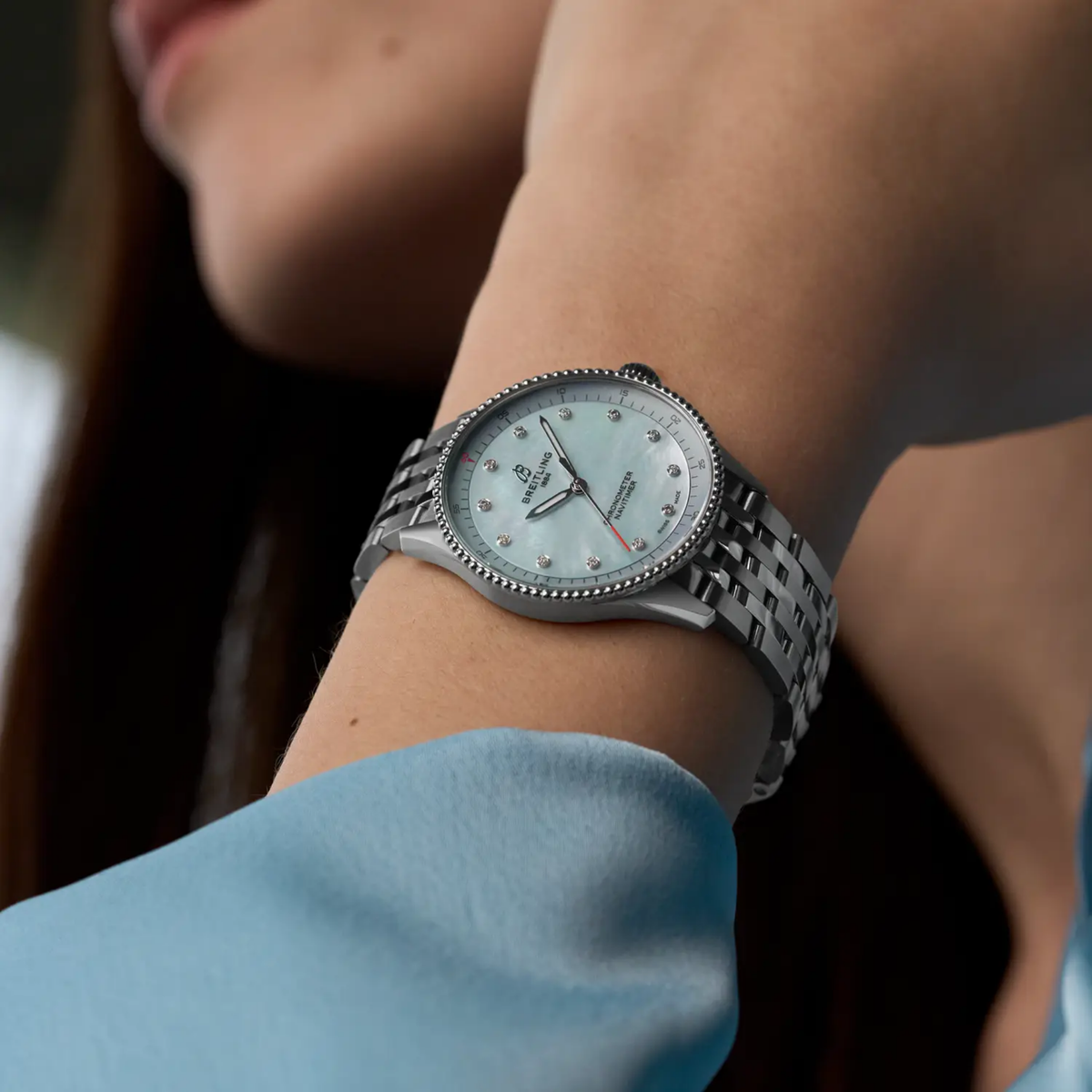 Breitling Navitimer Automatic light blue mother of pearl dial watch worn on wrist with stainless steel bracelet