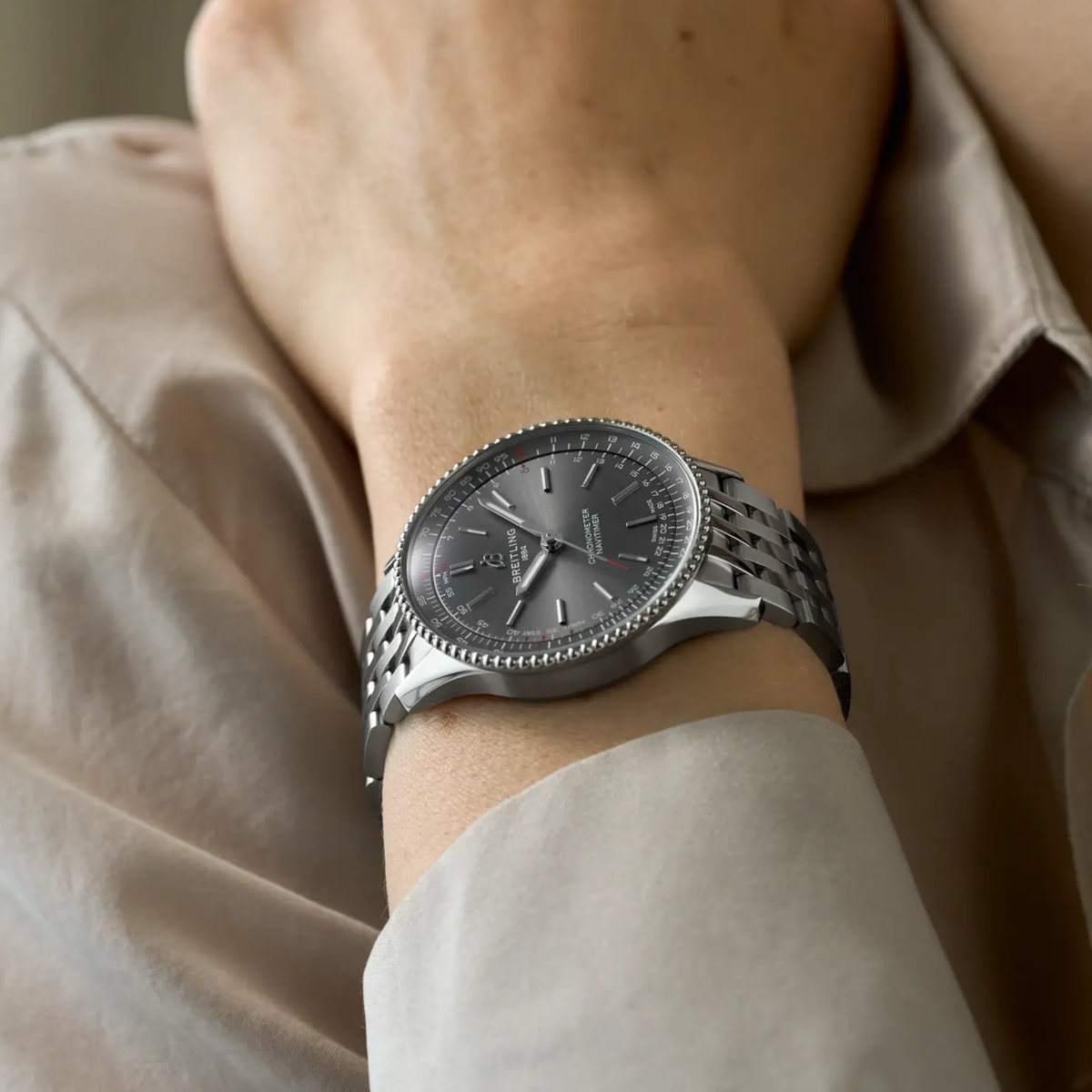 Breitling Navitimer grey dial stainless steel bracelet watch styled on wrist with a clean, sophisticated look