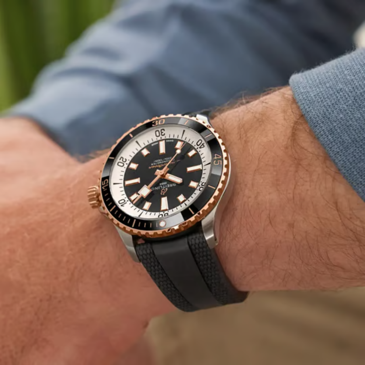 Breitling Superocean black dial diver watch on wrist with black rubber strap and rose gold accents