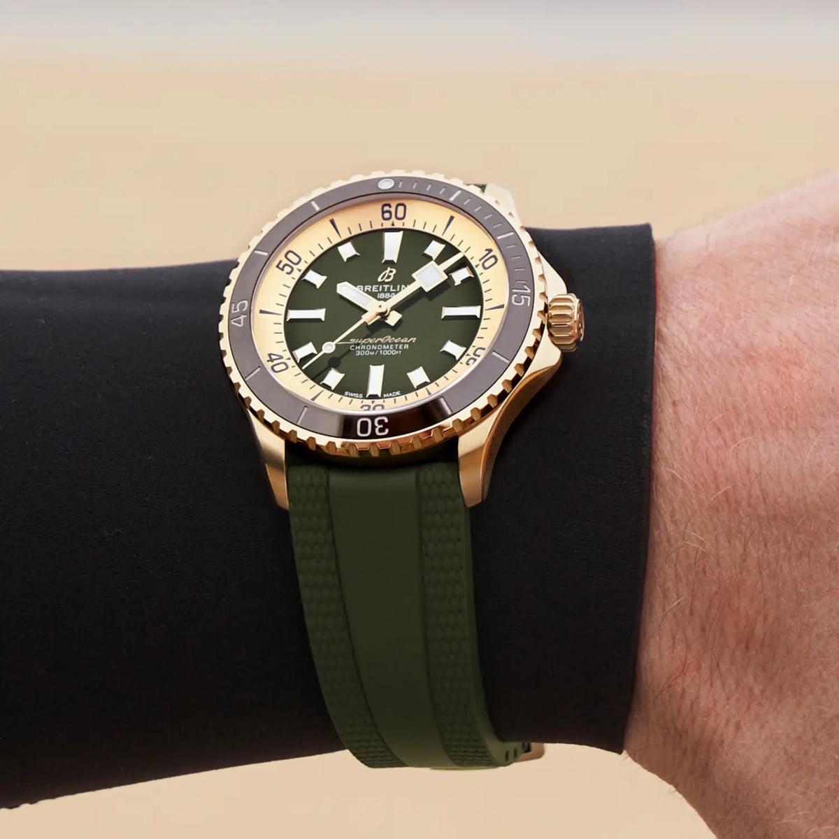 Breitling Superocean green dial gold watch on wrist with green rubber strap sporty diver style
