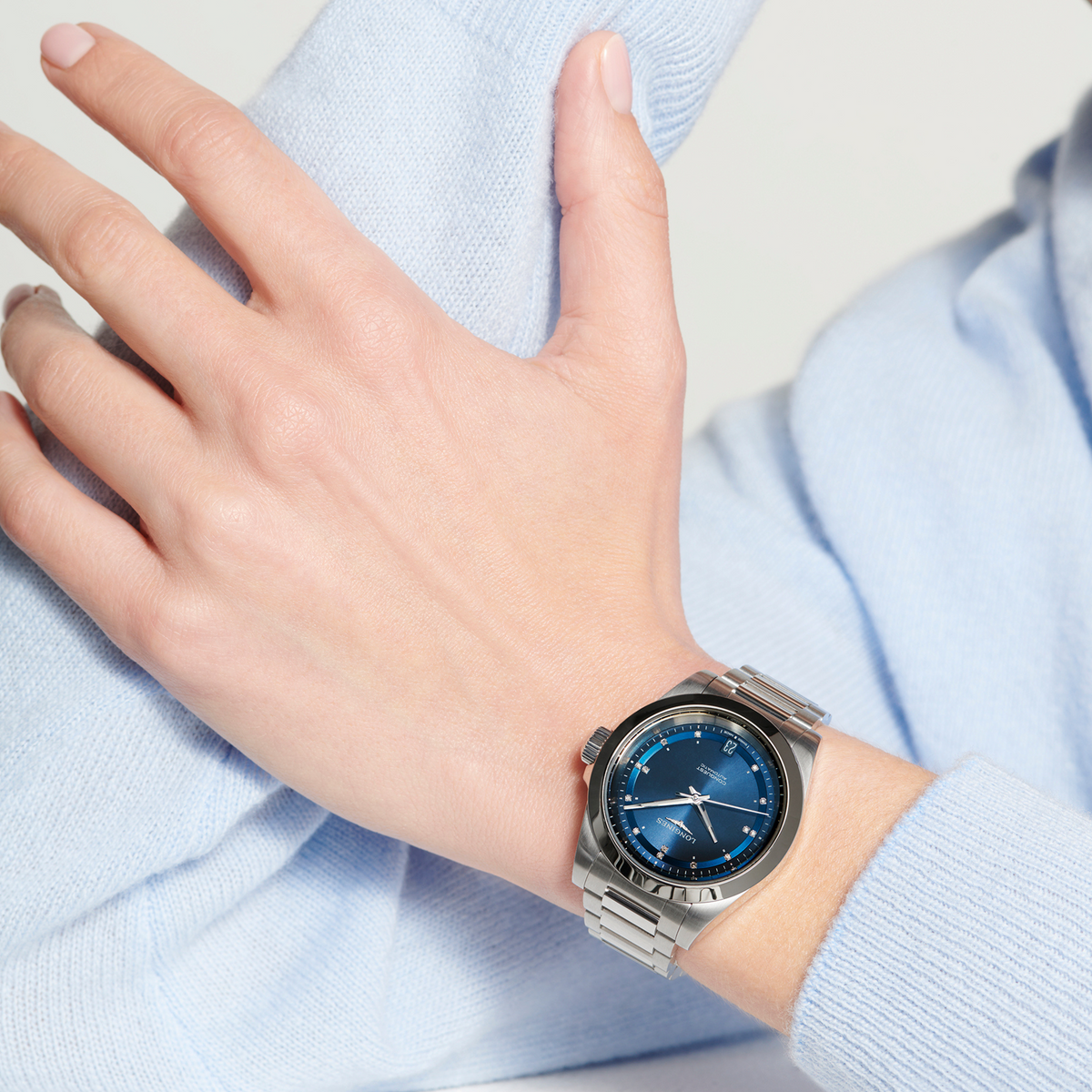 Longines Conquest blue dial automatic watch worn on the wrist with diamond detailing and polished stainless steel finish
