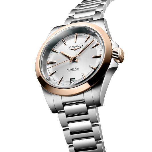 close up of the Longines Conquest silver sunray dial with rose gold hands, hour markers and date window

