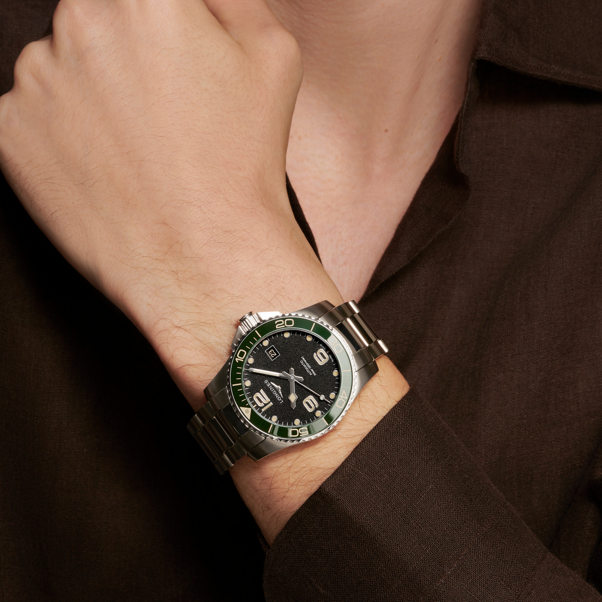 Longines HydroConquest sports watch worn on the wrist featuring a green bezel, black dial and stainless steel bracelet
