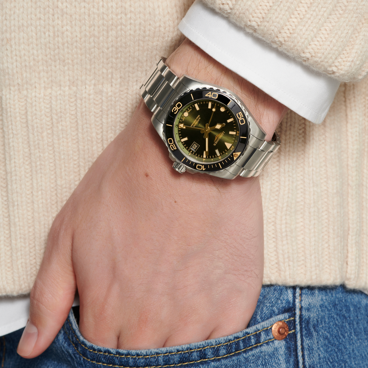 Longines HydroConquest GMT watch worn on the wrist featuring a green sunray dial, black bezel and sporty stainless steel bracelet
