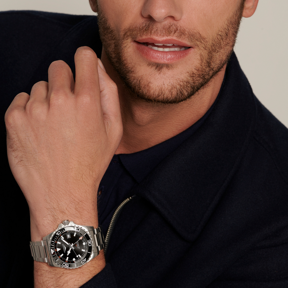 Longines HydroConquest GMT watch worn on the wrist featuring a black dial, orange GMT accents and stainless steel bracelet
