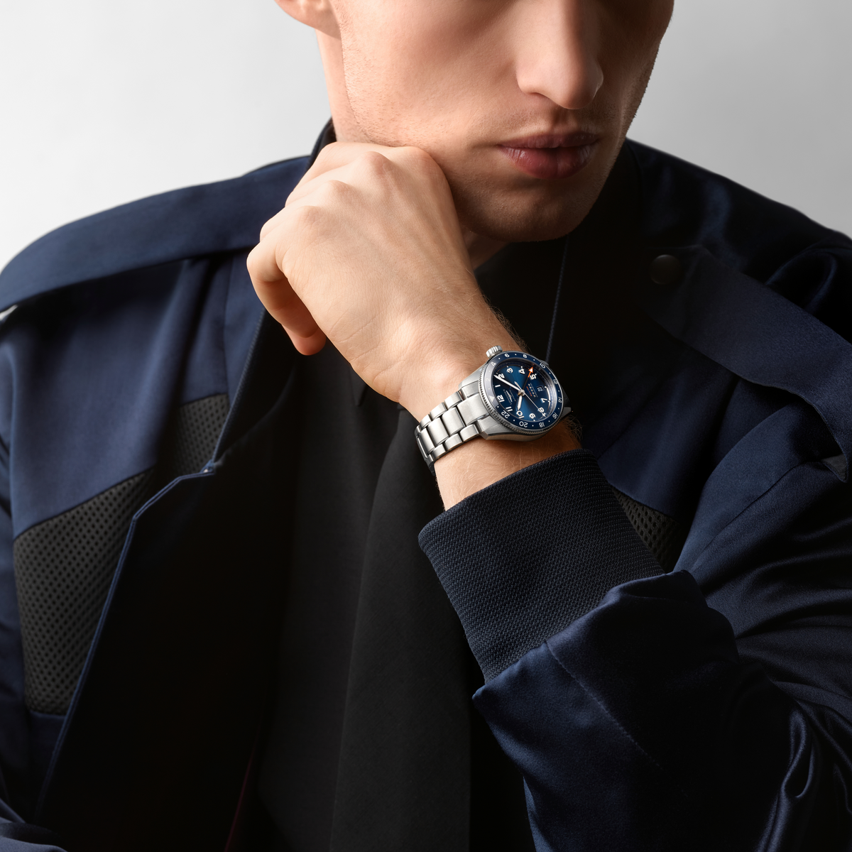 lifestyle image of Longines blue dial GMT chronometer watch worn on a wrist showcasing the blue ceramic bezel and sporty steel bracelet
