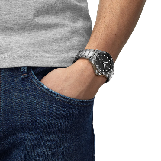 the watch worn on the wrist, showcasing the minimalist black diver-style dial, robust stainless steel bracelet, and confident everyday sports-watch presence
