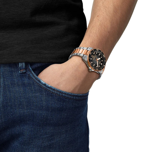 the watch worn on the wrist, showcasing the black textured dial, rose gold-tone accents, and robust two-tone bracelet that create a striking everyday dive-watch presence