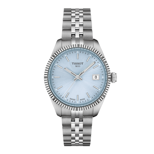 Tissot stainless steel watch featuring a light blue sunray dial, slim silver-tone baton hour markers, a fluted bezel, and a date window at 3 o’clock, finished with a brushed and polished multi-link bracelet
