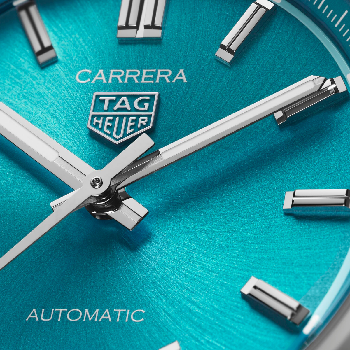 close-up of the teal dial showcasing the sunray finish, applied indices, sleek hands and date window at 6 o’clock