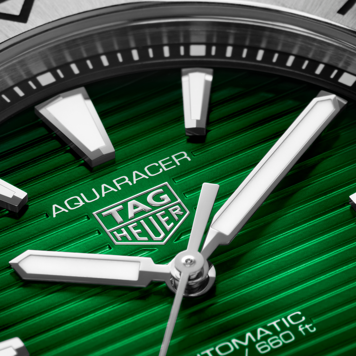 close-up of the green dial showcasing the horizontal stripe texture, bold luminous hour markers, hands and date window at 6 o’clock