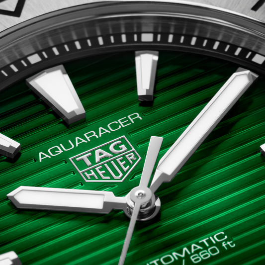 close-up of the green dial showcasing the horizontal stripe texture, bold luminous hour markers, hands and date window at 6 o’clock