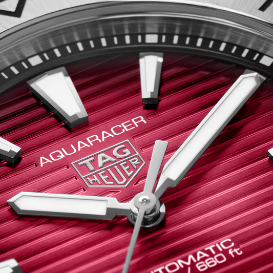 close-up of the red dial showcasing the horizontal stripe texture, luminous hour markers, hands and date window positioned at 6 o’clock