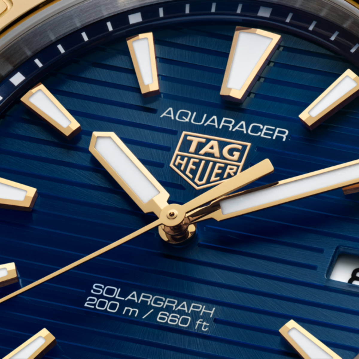 close-up of the blue dial showcasing the horizontal stripe texture, gold-tone hands and hour markers, central seconds hand and date window at 3 o’clock