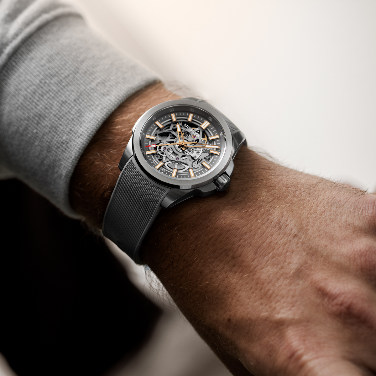 Side profile of the Norqain Independence Skeleton Chronometer Watch highlighting the robust stainless steel construction, signed crown, flexible grey rubber strap and contemporary sports watch styling.