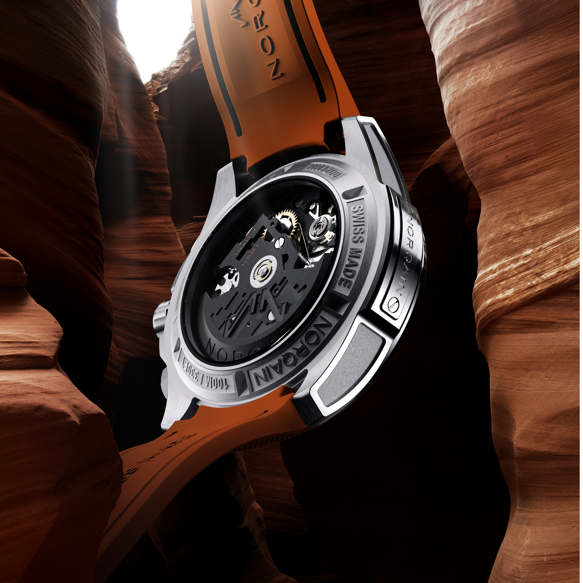 Close-up of a mechanical watch with a detailed back cover against a rocky background